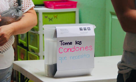 Caja sobre mesa dice: "Tome los condones que necesita"