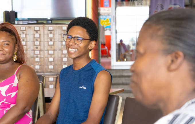 Un chico y una chica afrodescendientes conversan con una adulta mayor en la Biblioteca Pública de Limón