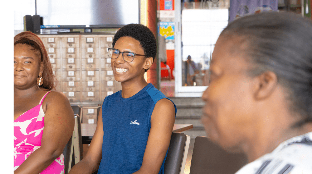 Un chico y una chica afrodescendientes conversan con una adulta mayor en la Biblioteca Pública de Limón